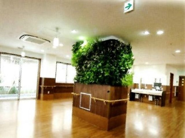 中央に緑の装飾のロビー ホール 広々としたロビーには、緑あふれる装飾があり、訪れる方々に安らぎを提供します。椅子も配置されており、休息の場としてもご利用いただけます。