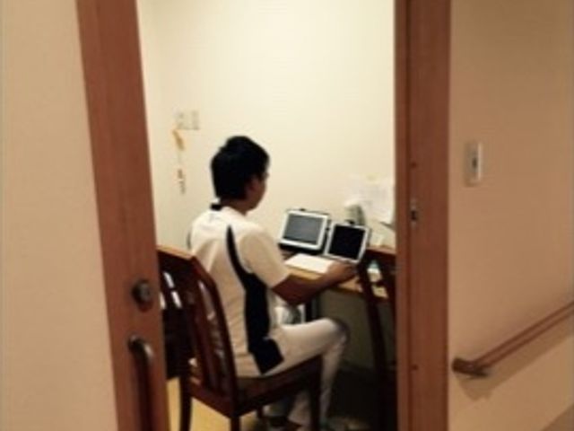 仕事中のスタッフ居室 スタッフ 落ち着いた雰囲気の居室で、白衣を着たスタッフが丁寧に業務にあたっています。快適な環境での就業をご検討いただければ幸いです。