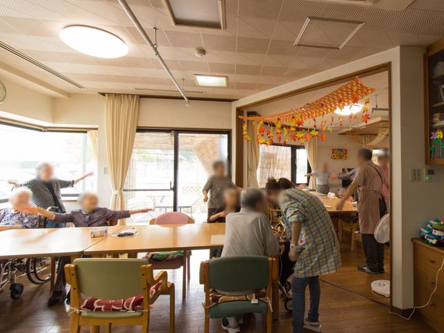 活気ある共同空間ダイニング リビング ゆとりあるダイニングで、利用者とスタッフが和やかに過ごしています。食事や活動が楽しめる温かい環境です。