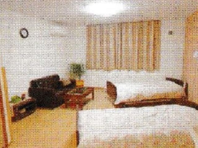 清潔感のある明るい居室 居室 ゆったりとしたベッドが配置された居室です。木目調の家具と暖かみのある色合いで、安心感を提供しています。