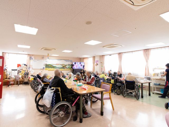 共有スペースの様子 食堂 明るく広々とした多目的室で、利用者の皆さんが日々の憩いの時間を過ごしています。車椅子に座る方々も自由に活動できる環境です。