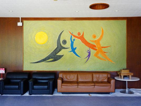 広々としたフロアには、人の形を描いた壁一面の大きな絵が飾られている。1人掛けのソファーが2つ、3人掛けのソファーが1つ置かれている。