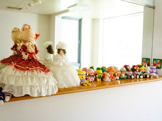 廊下にある大きな鏡の前の棚には、たくさんの人形やぬいぐるみがならべられている。ドレスを着た大きな人形が2体並べられている。