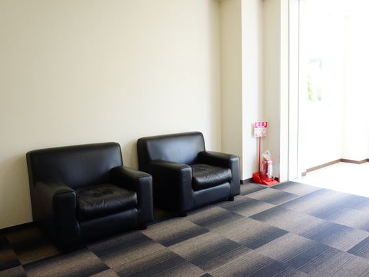施設内の廊下は、幅広くスペースが確保されている。廊下の隅には、黒くてクッション性のある一人掛けのソファーが2つ設置されてる。