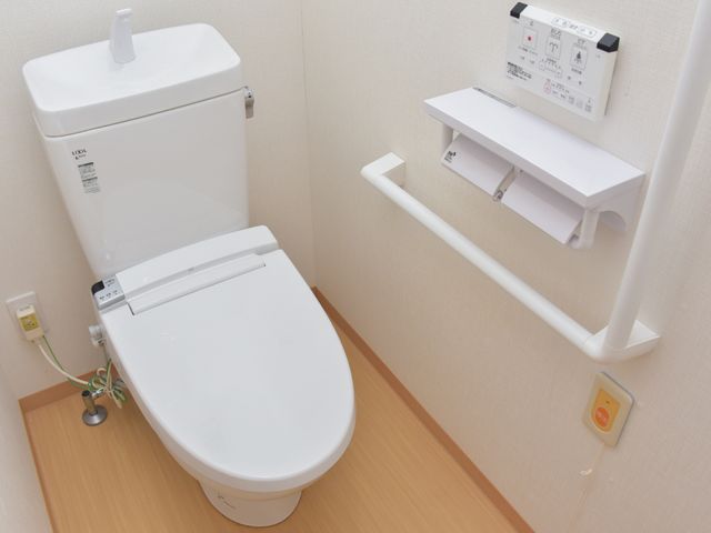 バリアフリートイレ設備 居室トイレ 手すり付きのトイレは、足腰が不自由な方にも使いやすい設計になっており、緊急時には呼び出しボタンもすぐそばにあります。安全で快適な日々のための配慮がされています。