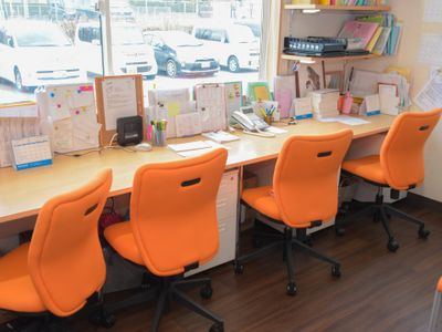 オレンジの椅子が並ぶ事務室