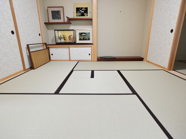 清潔な和室の一角 茶室 落ち着いた色合いの和室で、伝統を感じる空間を提供しており、ゆったりとお過ごしいただけます。窓際には小物が飾られており、温かみのある雰囲気です。