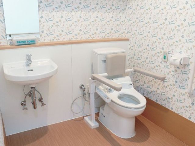 バリアフリートイレ設備 トイレ2 持ち手付きのトイレと安全を考えた洗面台が設置され、利用者の自立支援に配慮された空間です。安全で快適な環境作りを目指しています。