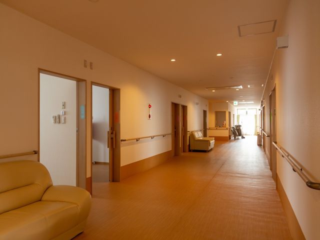安全な廊下の空間 通路 ゆったりとした廊下には手すりが整えられ、居心地の良い椅子も設置されています。スタッフとご利用者様が共に過ごす明るく開放的な場所です。