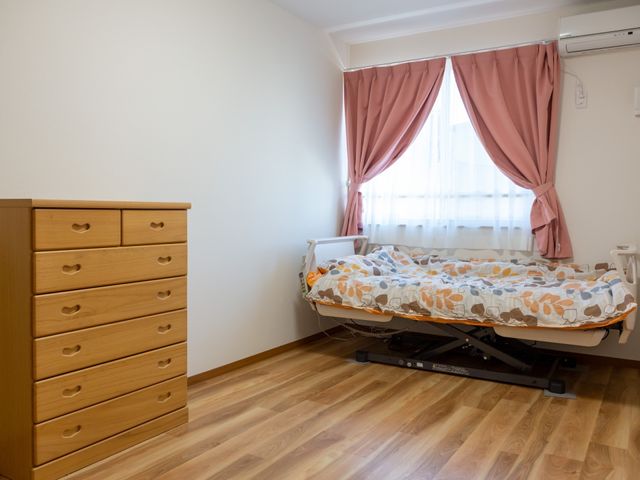 居室のベッドとタンス 居室 広々とした明るい部屋には、使い勝手のよいタンスと高さ調節可能なベッドが設置されており、快適にお過ごしいただけます。
