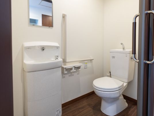 各居室に備え付けの個人用トイレ。室内には弁機本体のほかにもコンパクトな白い手洗い器と鏡も設置されている。