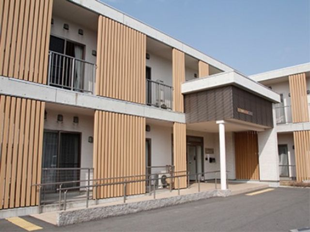 木目調のモダンな居室 外観 明るく清潔感のある居室が並び、落ち着いた色合いが心地よい空間を創出しています。車椅子でも安心して移動できる広々とした通路が配慮されている点も魅力です。