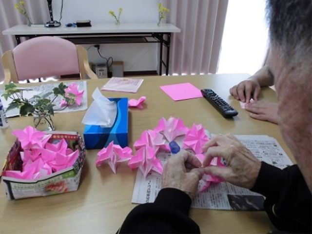 手作業を楽しむ様子 折り紙 利用者が折り紙をしながら穏やかな時間を過ごしている多目的室です。ここでは日々の楽しいレクリエーションが提供されています。
