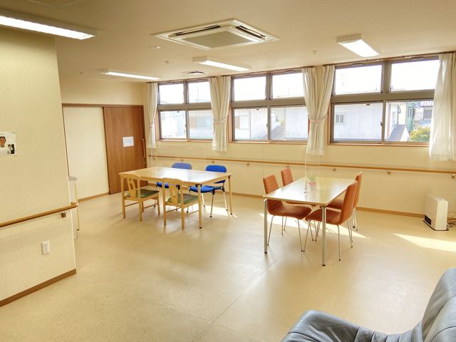 明るい共有スペース ダイニング ゆったりとした食堂で、利用者の方々がリラックスして過ごされています。天井の飾りやテレビが、居心地の良い環境を提供しています。
