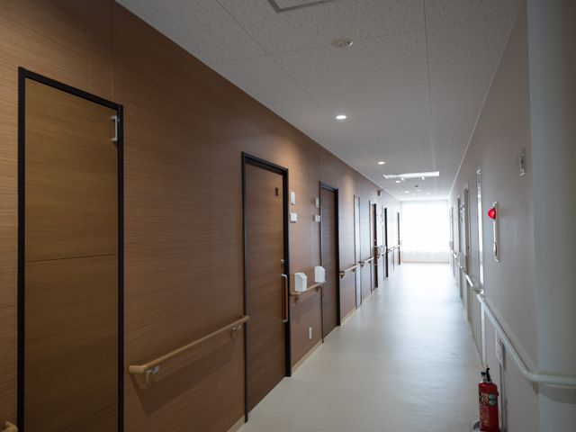 清潔感のある廊下 通路 広々とした通路は清潔感があり、明り取りの窓から自然光が差し込んでいます。利用者の方々の心地よい移動を支える設計です。