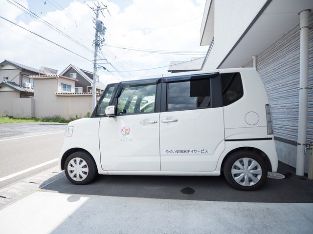 白い送迎車両駐車中 車 ゆったりとした送迎車両のご用意があり、利用者様の移動をサポートしております。安心してご就業いただける環境です。