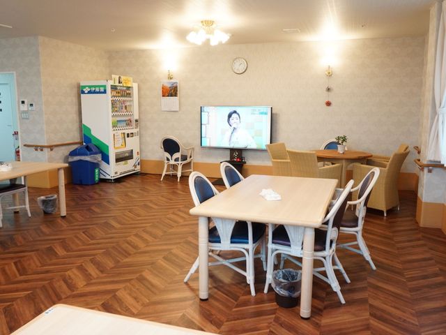 温かみのある休憩室風景 共有スペース 明るい空間で配されたテーブルと椅子が心地よい雰囲気を醸し出しています。壁掛けテレビでの情報提供や余暇の楽しみも充実しております。