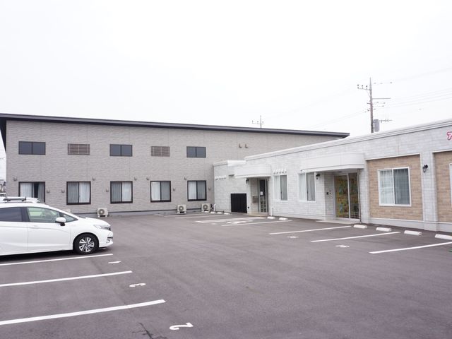 広々とした駐車場のある外観 外観 整然とした駐車場を持つ建物で、ゆったりとした環境での就業が見込めそうです。明るい雰囲気の入り口が気持ちを和ませてくれます。