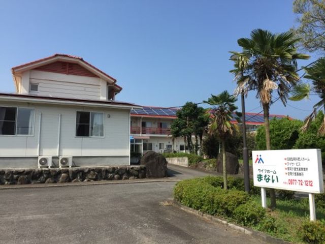 青空の下の建物と看板 外観 ゆったりとした敷地に佇む建物は、明るい日差しをたっぷりと浴びています。緑豊かな環境で働くやりがいを感じてみませんか。