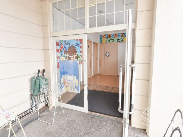明るいエントランスの風景 出入口 ガラス扉で開放的な雰囲気が漂い、施設への入口が明るく迎えます。訪れた方が安心して足を踏み入れられる、暖かな印象のエントランスです。