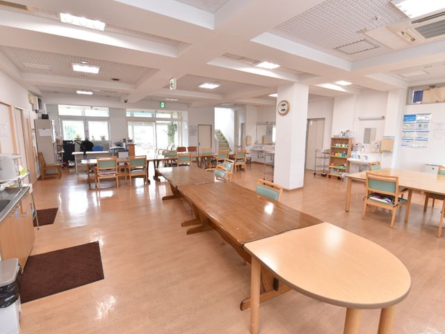 広々とした明るい食堂 共有スペース 広々とした食堂では、心地よい自然光が差し込み、スタッフの方がテキパキと作業をされています。利用者の方々が温かい雰囲気の中で食事を楽しめる設計です。