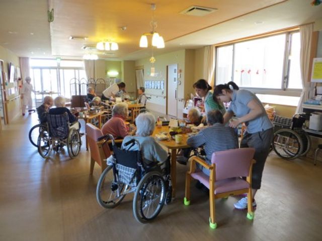 明るい食堂 リビング 手当たり次第のケアではなく、こだわりを持った食事時間を提供しています。利用者とスタッフが一体となった明るい食事風景です。