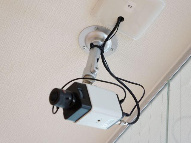 廊下の監視カメラ 監視カメラ 施設内は、常に安全が確保されるよう、見守りのための監視カメラを設置しています。働いていただくスタッフのセキュリティも考えた環境です。
