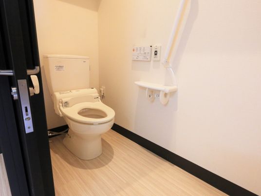 施設の写真 トイレの便器には温水洗浄便座を採用しており、壁には操作ボタンが設置されている。冬場の寒い時期でも温かく快適である。