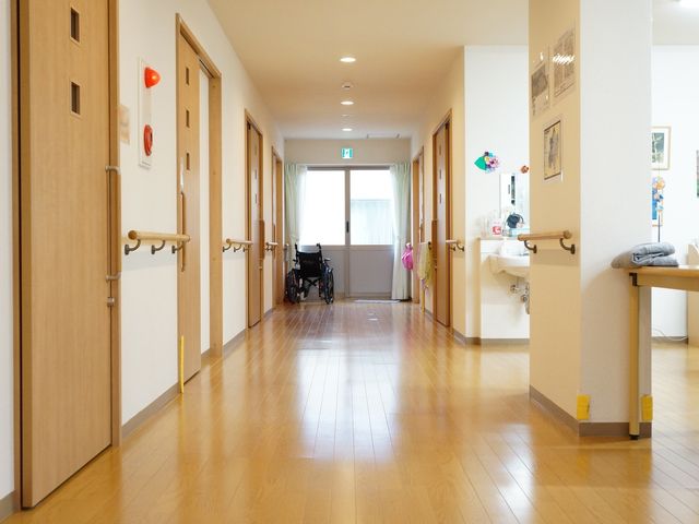 光が差し込むきれいな廊下 通路 手すり付きで床も明るく、車椅子も置いてある安全で清潔な通路です。皆さんの快適な生活をサポートする設計が随所に見受けられます。