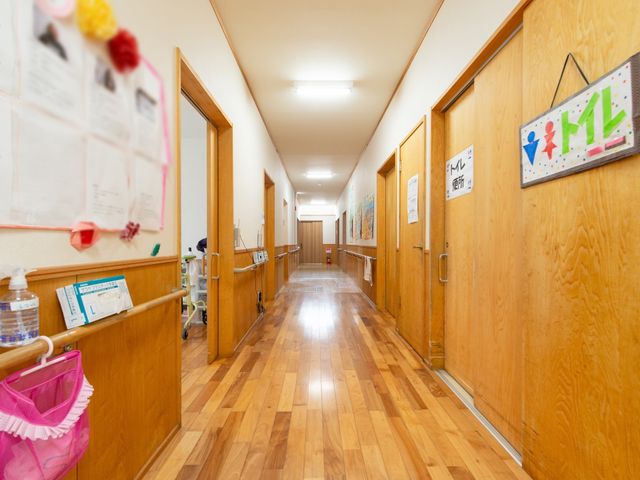 明るい木目調の廊下 廊下 手すりが備えられた温かみのある廊下です。壁には掲示物があり、季節感を感じさせる工夫がされています。