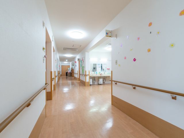 明るく清潔な廊下 廊下 ゆったりとした通路には、明るい日差しが差し込み、皆さんの安全を考えた手すりが設置されています。壁に飾られた花の絵が笑顔を引き出します。