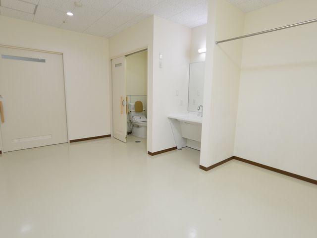 広々とした清潔なトイレ 個室内部 手すりと広い空間が配置され、使いやすいトイレです。動きやすさを考慮した設計で、安心してお使いいただけます。