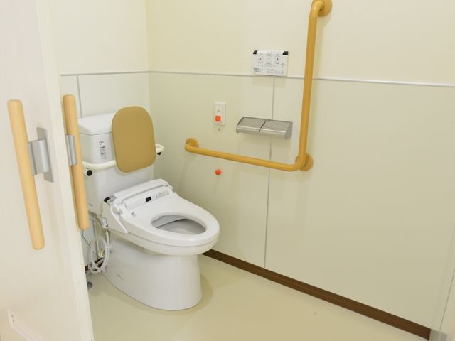 バリアフリー設計のトイレ 個室内のトイレ 手すり付きで安全なトイレです。全てが手の届くところに配置され、利用者の自立を支えています。