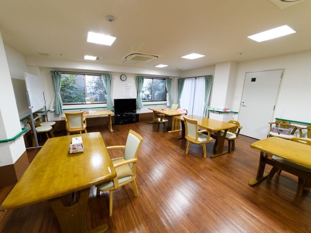 広々とした明るい食堂 食事・談話スペース 木のテーブルが並ぶ広い食堂では、皆での食事や交流が楽しめる設計になっております。窓からは自然光が差し込み、温かみのある空間を提供しています。