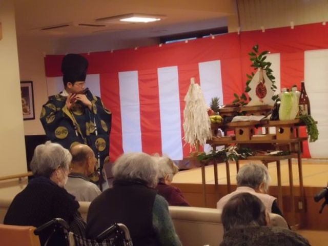 和風のイベントスペース 共有スペース 和服を着た方が催しを行っており、見守る利用者の方々が和やかな雰囲気で集まっています。こうした交流が活性化の場となっています。
