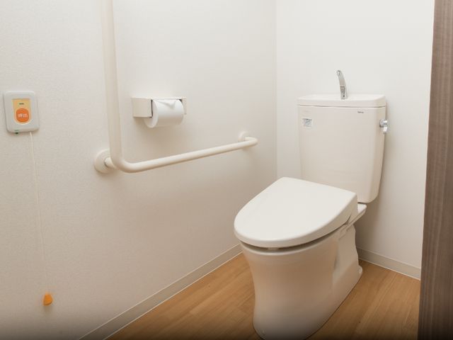 バリアフリートイレ設備 居室トイレ 手すり付きの快適なトイレです。緊急呼出しボタンがあり、安心してご利用いただける環境を整えています。
