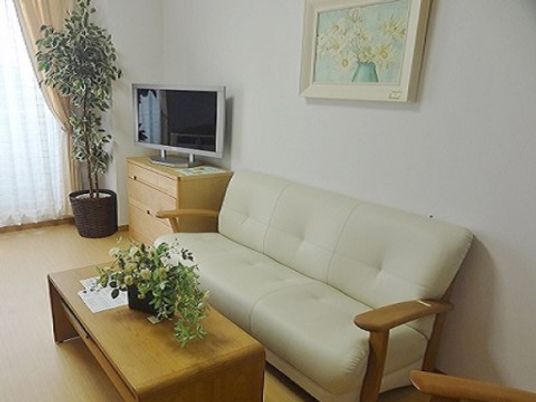 施設の写真 明るい居室の壁際には幅の広いソファーが設置されており、入居者様は来訪者様と座りながら談笑することができる。