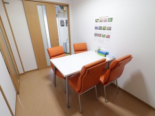 施設の写真 談話室には４人掛けのテーブルと椅子が設けられている。扉にはスリットが入っており、採光の効果がある。完全個室のためゆっくりとお話ができる。