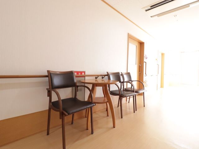 廊下の椅子並び 通路 木製の椅子が並べられた落ち着いた雰囲気の廊下です。ここで少し休憩しながら心地よい日差しを感じられます。
