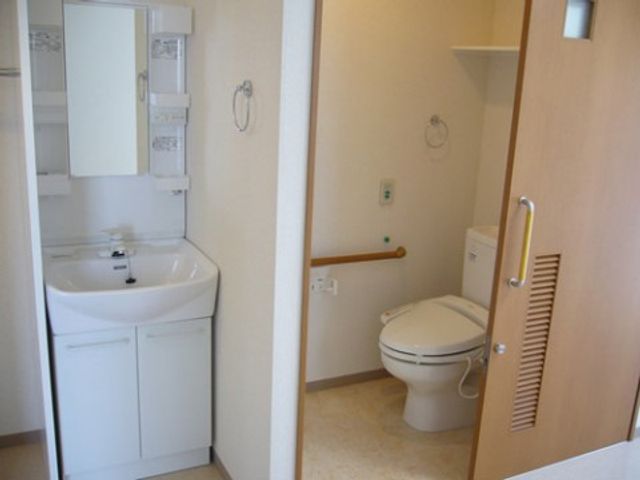 清潔なトイレと洗面台 トイレ 手すりが設置された清潔なトイレ空間です。安全かつ快適にご利用いただける設計になっています。