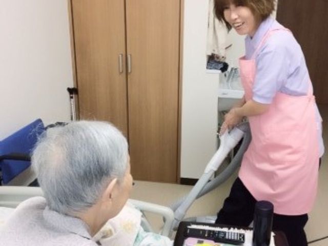 笑顔のケアスタッフと利用者 職員のお仕事風景2 笑顔でサービスを提供するケアスタッフの姿です。利用者とのコミュニケーションも大切にしています。