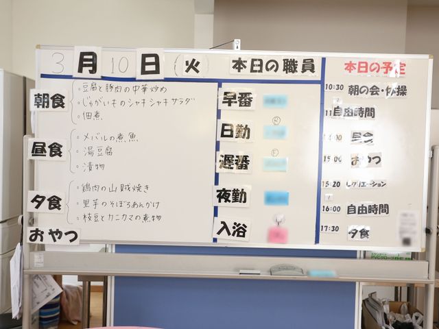 活動案内ボードのアップ ホワイトボード この掲示ボードは、日々の活動スケジュールを示しており、きめ細やかな運営が伺えます。スタッフとして働く方々が把握しやすくなっています。