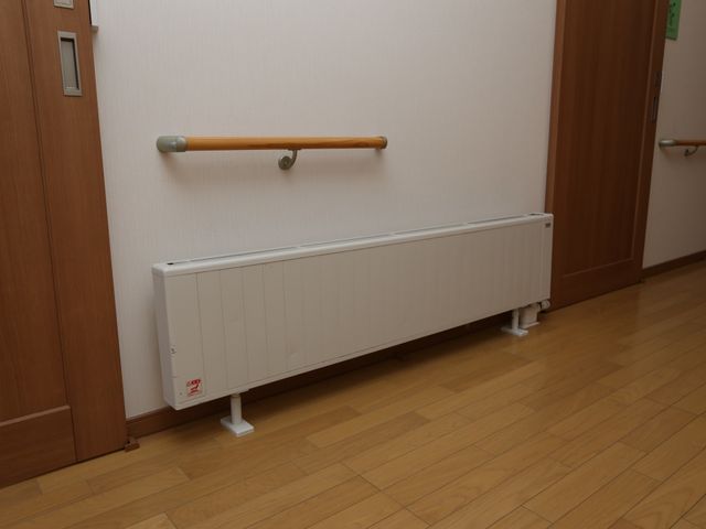 廊下の手すりと暖房器具 廊下 廊下には手すりが設置され、ご高齢の方の移動をサポートします。暖房設備も整っており、快適な環境づくりがされています。
