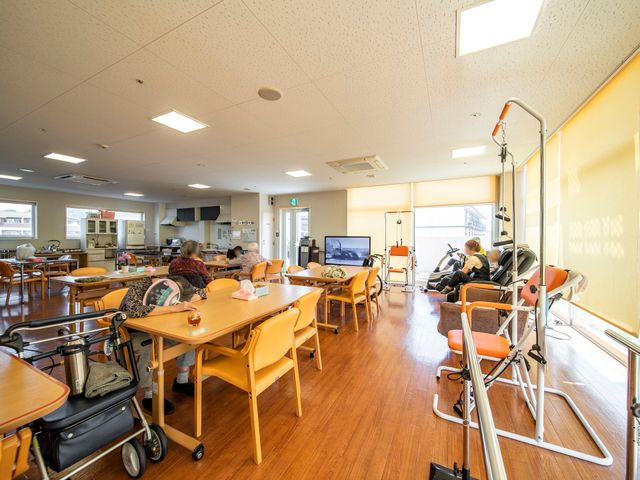 共有スペースの日常風景 食堂 開放感あるダイニングでのんびりと過ごされている方々。テレビや窓の光が柔らかく照らす温もりのある空間です。