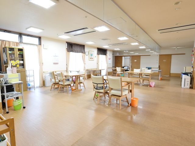 共有スペースの明るい居室 リビングルーム ゆったりと配置された椅子とテーブルから過ごしやすい空間が伝わります。仕事を通じて、このような環境を支えるやりがいを感じてみませんか。