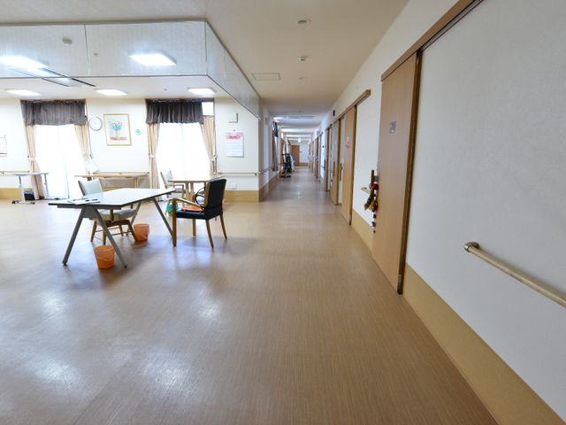 廊下と共有スペースの景色 リビングと通路 広々とした廊下には、柔らかな光が差し込み快適な雰囲気です。手すりも設置され、安全に配慮した設計になっています。