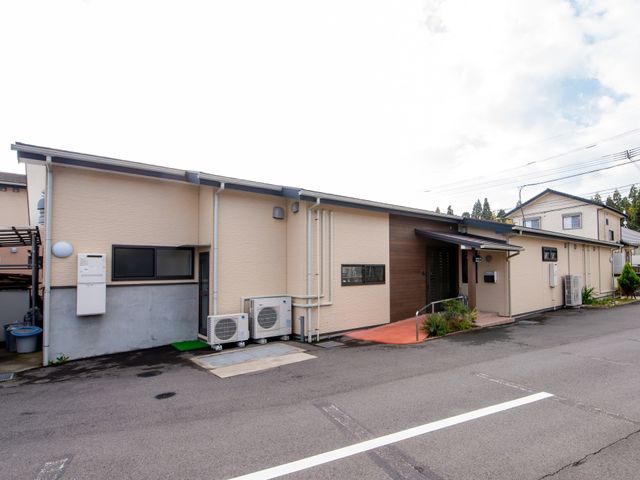 一階建ての建物エントランス 外観 ご利用者の方々が安心して暮らせる、落ち着いた雰囲気のエントランスです。職員が温かく迎えてくれる環境を整えています。