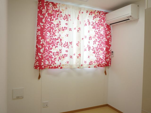 明るい窓とエアコンの部屋 個人部屋 花柄のカーテンが鮮やかで、快適に過ごせる明るい空間です。