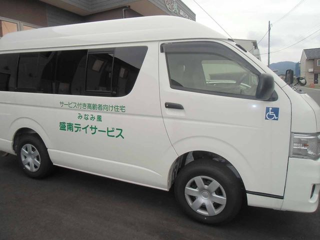 送迎バス 外観 送迎バスは利用者の移動を快適にサポートします。車椅子マークもあり、安心してご利用いただけます。