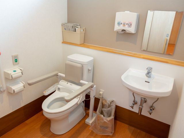 バリアフリーなトイレ空間 トイレ 手すり付きの清潔なトイレ。広々としており、安心してご利用いただける設計です。